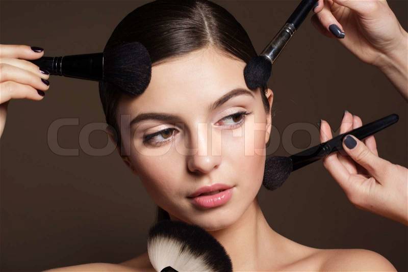 Portrait of a naturally beautiful woman visagist is holding brushes for makeup that makes skin flawless and perfect, stock photo