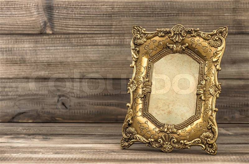 Golden baroque style picture frame on wooden background, stock photo