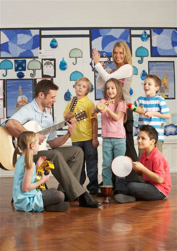 Teachers Playing Guitar With Pupils Having Music Lesson In Classroom, stock photo