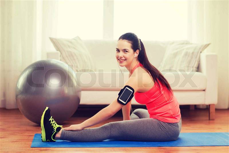 Fitness, sportm home and dieting concept - smiling teenage girl with armband execising at home, stock photo