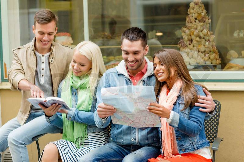 Travel, vacation and friendship concept - group of smiling friends with city guide and map exploring town, stock photo