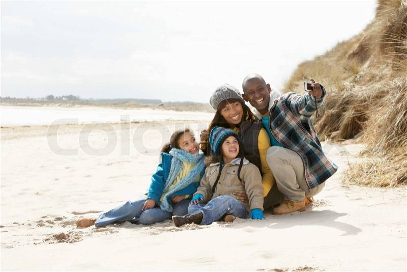 Black family taking photos on a beach, stock photo