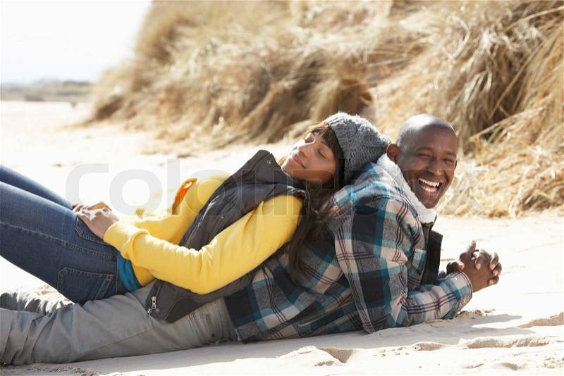 Couple back to back on a beach, stock photo