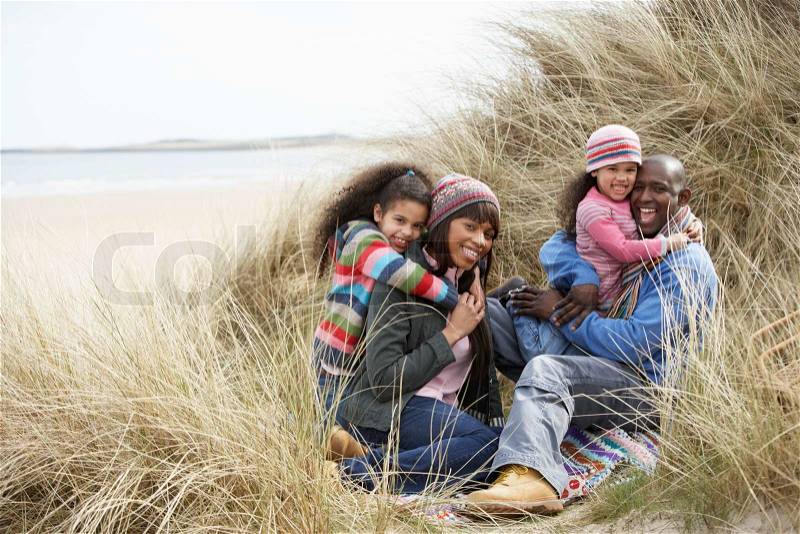 Happy black family hugging on a beach, stock photo