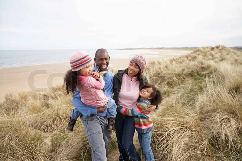 Happy black family embracing on a beach, stock photo