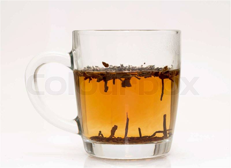 A transparent glass filled with brown leaves and yellow liquid, stock photo