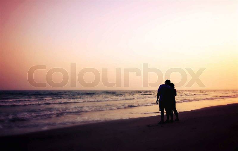 Silhouette of couples hugging on the beach on the beach with sunrise in the sea for valentine\'s day, stock photo