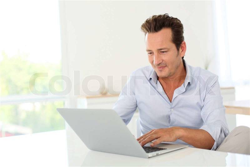 40-year-old man using laptop computer at home, stock photo