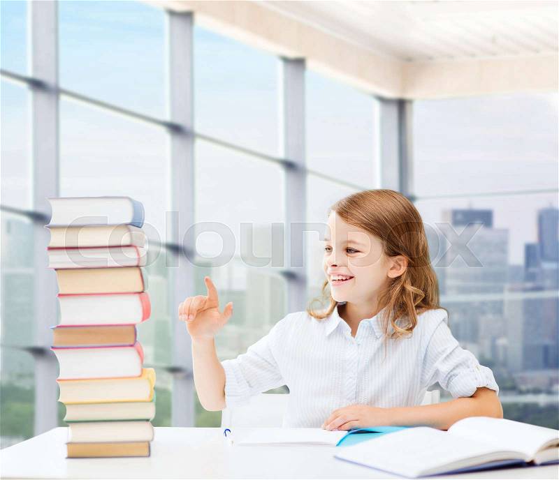 Education, people, children and school concept - happy student girl sitting at table and counting books over classroom background, stock photo