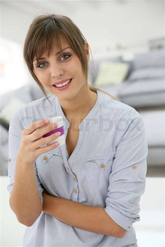 Smiling young woman standing in brand new apartment, stock photo