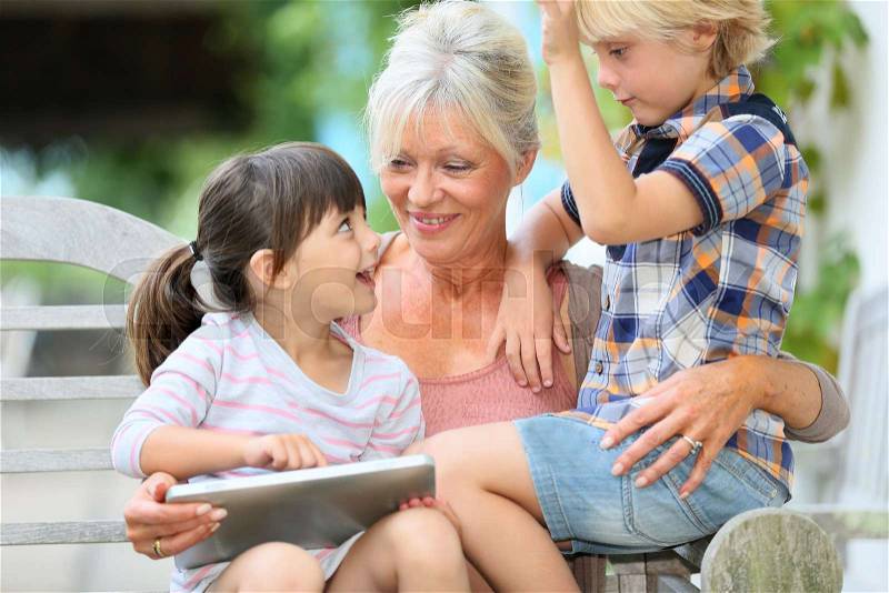 Grandmother with kids playing games on tablet, stock photo