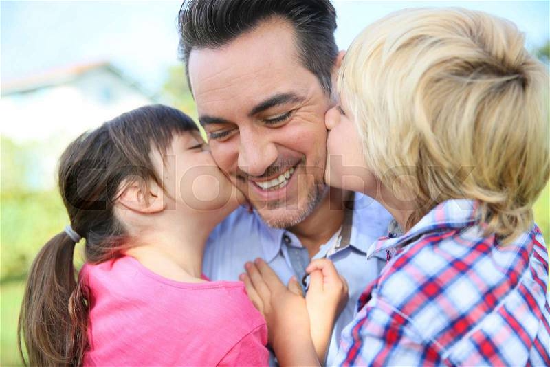 Portrait of kids giving a kiss to their daddy, stock photo