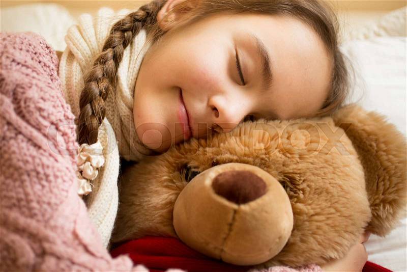Closeup portrait of little girl sleeping on brown teddy bear, stock photo