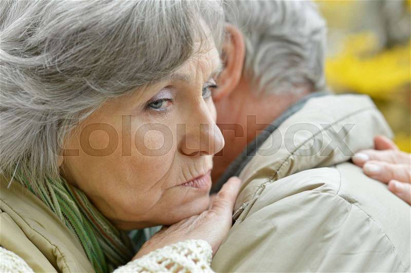 Sad senior couple in autumn park, stock photo