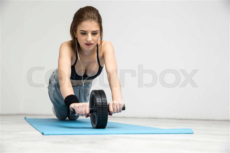 Young woman exercising fitness workout abdominal wheel, stock photo