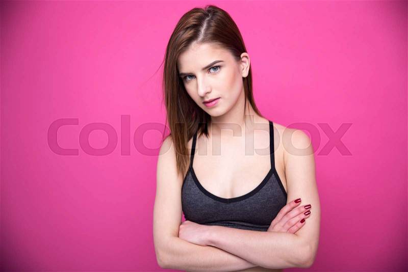 Portrait of a beautiful woman with arms folded over pink background, stock photo
