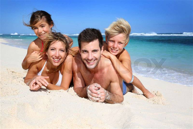 Portrait of happy family laying on the beach, stock photo