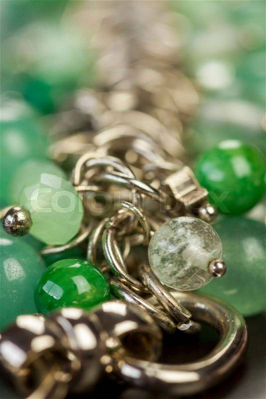 Close up view of pretty translucent green beads on an item of silver jewellery attached in a bunch to a ring by short chains with shallow dof in a fashion concept, stock photo