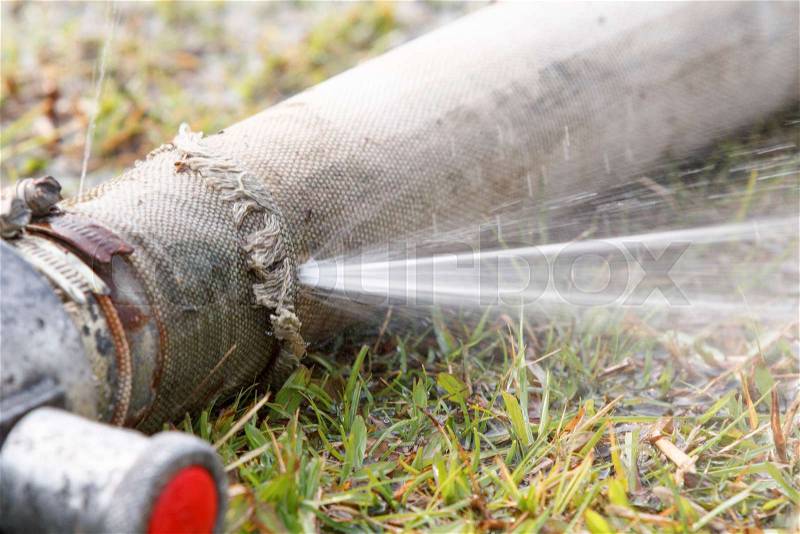 Wasting water - water leaking from a hole in a hose, stock photo