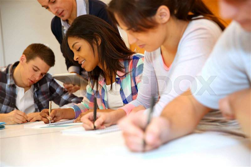 Group of teenagers in class writing an exam, stock photo