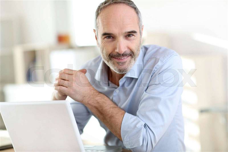 Senior businessman working on laptop computer, stock photo