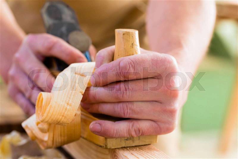 Carpenter working with a wood planer on workpiece in his workshop or carpentry, stock photo