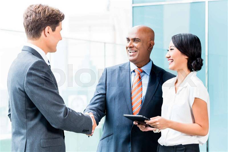 Indian CEO and Caucasian executive having business handshake in front of city skyline, stock photo