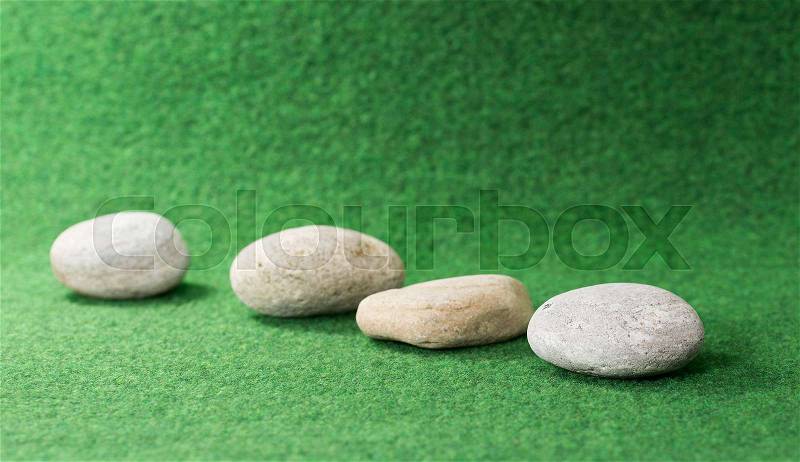 Row of stones on green background, stock photo