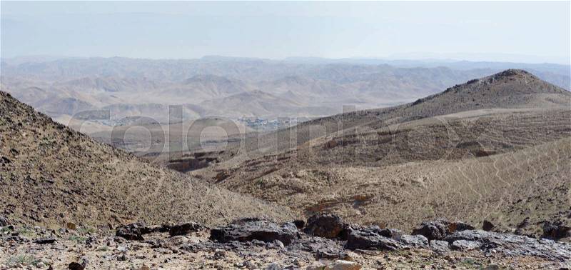 Desert landscape with far Bedouin camp on hazy day in Kidod Ceek near Arad in Negev desert, Israel, stock photo