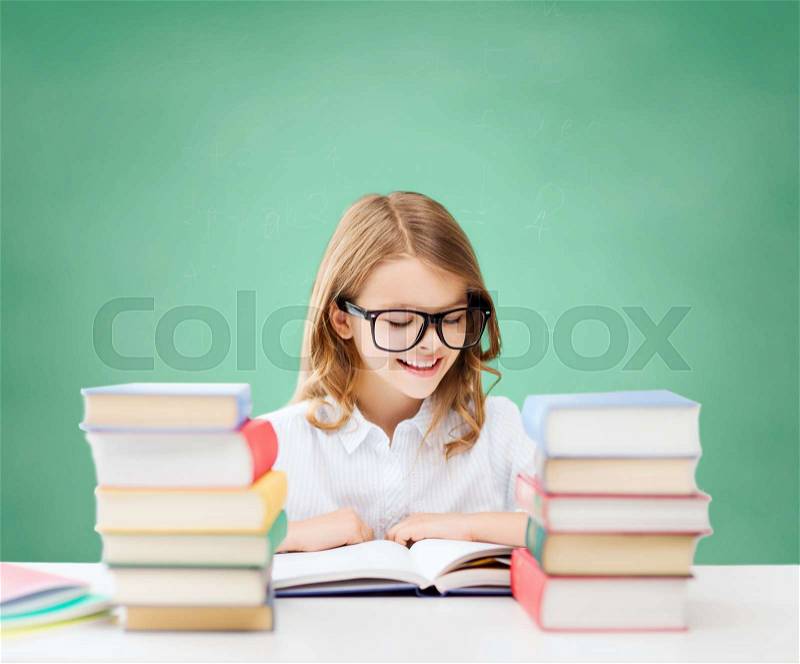 Education, people, children and school concept - happy student girl in eyeglasses reading book over green chalk board background, stock photo
