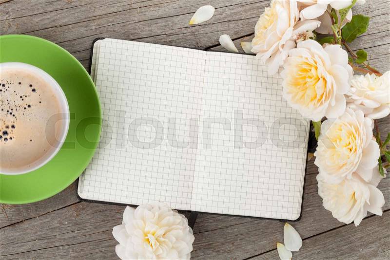 Blank notepad, coffee cup and white rose flowers on wooden table background, stock photo