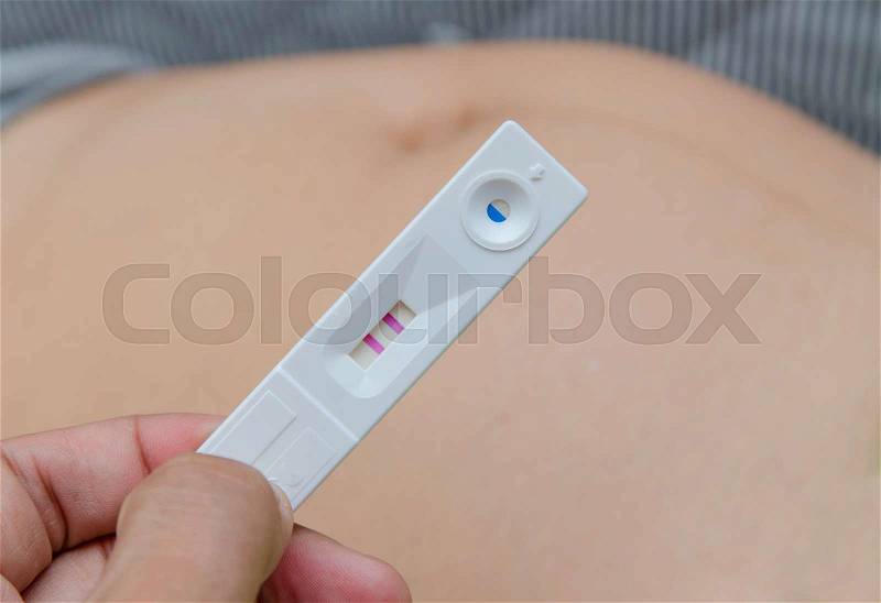 Holding positive pregnancy test with two red stripes, stock photo