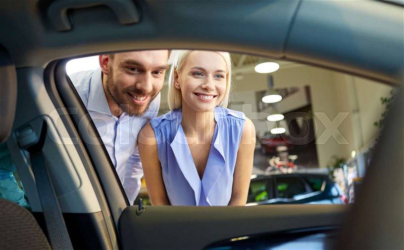Auto business, car sale, consumerism and people concept - happy couple buying car in auto show or salon, stock photo