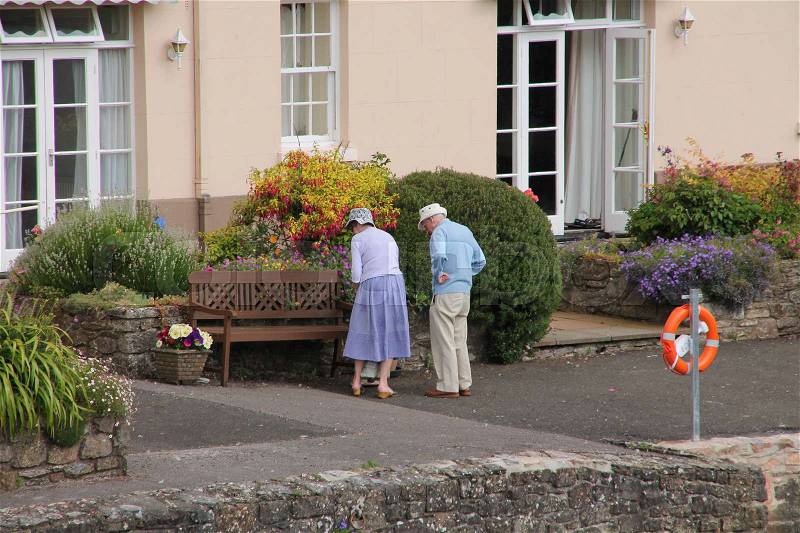 Retired couple, man and wife, look to the garden in the summer in England, stock photo