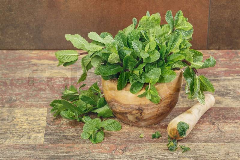 Mortar with fresh mint leaves. Fresh green mint in mortar on rustic wooden background, stock photo