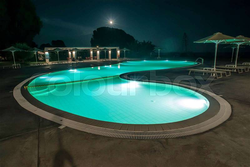 Pool, sunbeds and umbrellas at night. Night lights. Greece, Gythio, stock photo