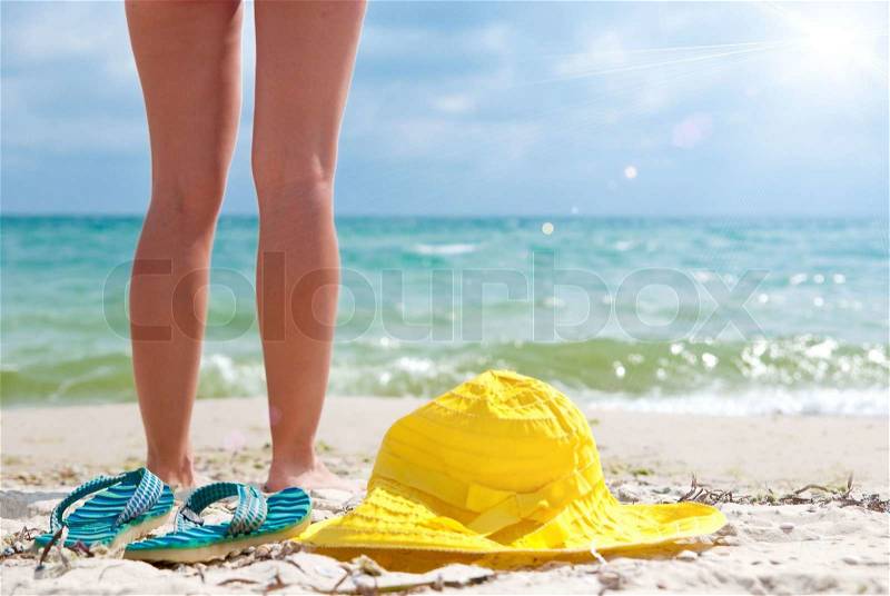 Flip-flop, hat and woman on the beach near sea. Focus on flip-flop, stock photo