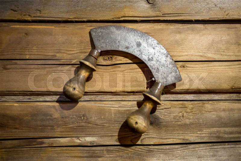 Closeup photo of old knife for herbs hanging on wooden wall, stock photo