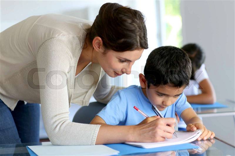 Teacher helping young boy with writing lesson, stock photo