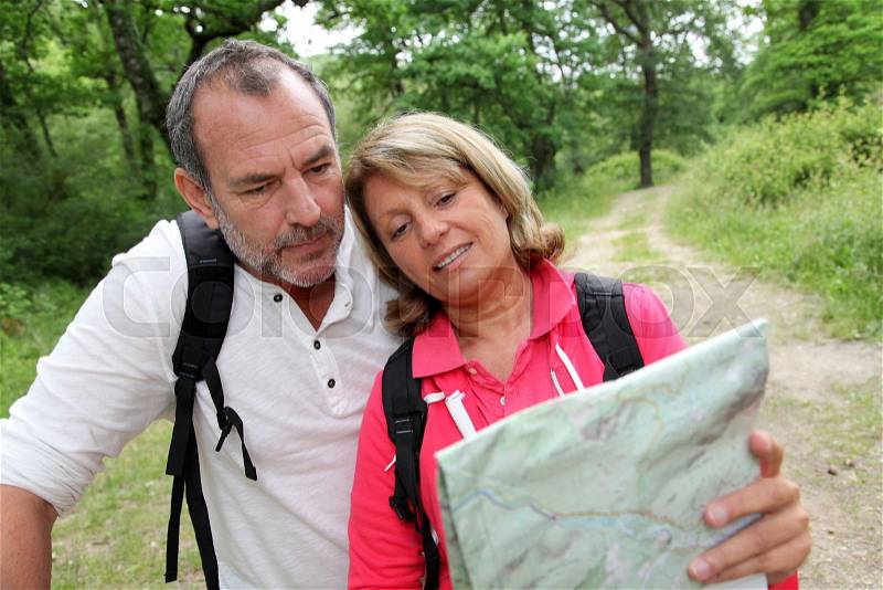 Senior couple rambling in forest with map, stock photo