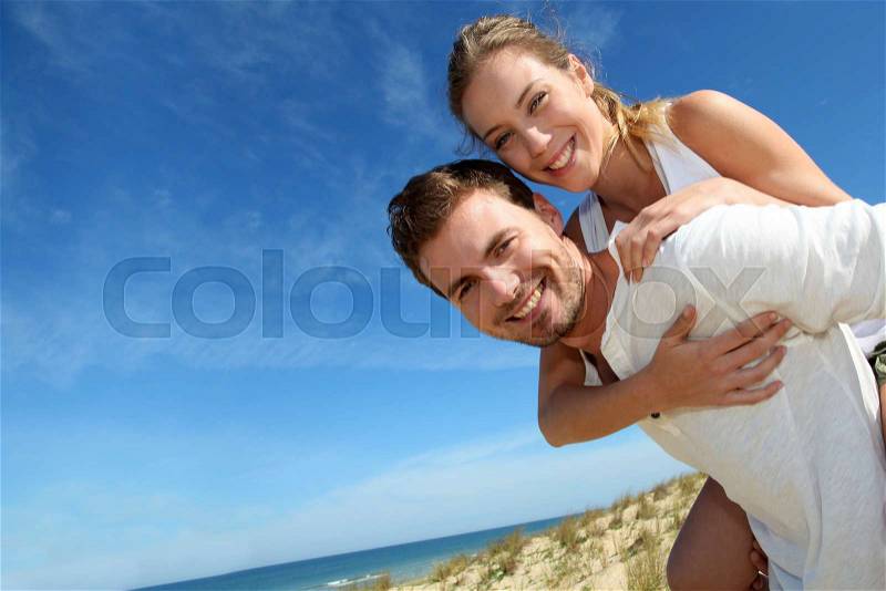 Man giving piggyback ride to girlfriend on a sand dune, stock photo