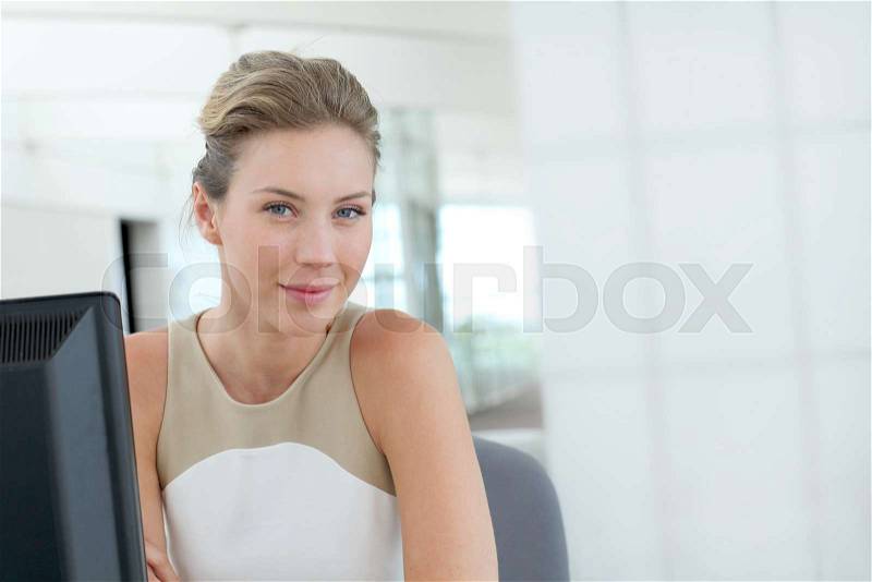 Beautiful blond office-worker sitting at her desk, stock photo