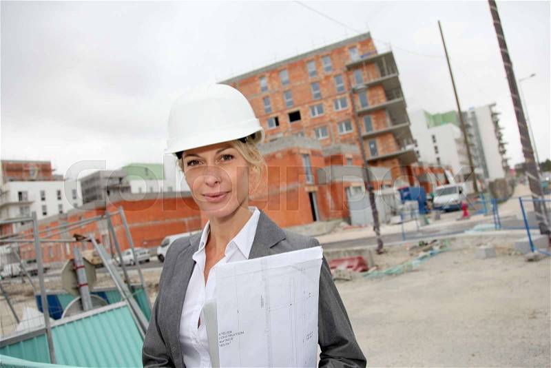 Woman engineer standing in front of building site, stock photo