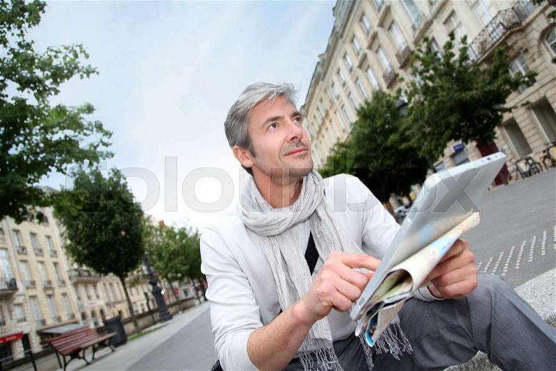 Cheerful handsome guy in town using electronic tablet, stock photo
