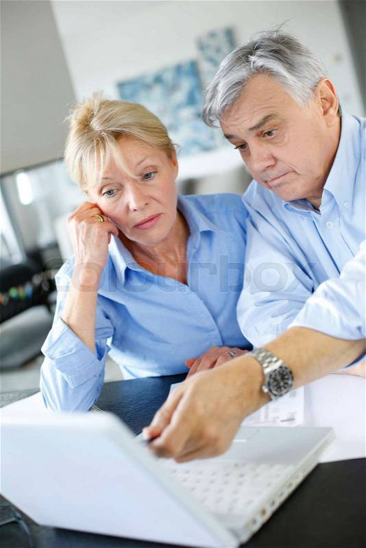 Senior couple inquiring bank website for help, stock photo