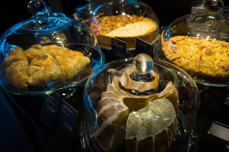 Cakes under bell-glass on display. bakery glass case full of different pieces of cakes, stock photo