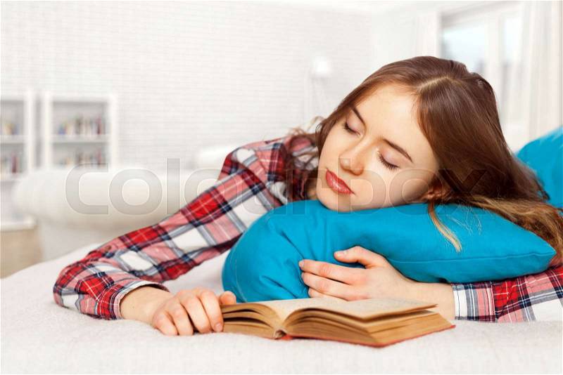 Young girl slepping with a book in bed, stock photo