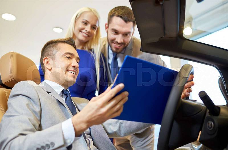 Auto business, car sale, consumerism and people concept - happy couple with car dealer in auto show or salon, stock photo