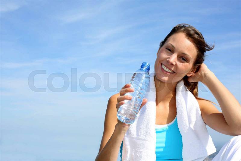 Thirsty fitness girl holding bottle of water, stock photo