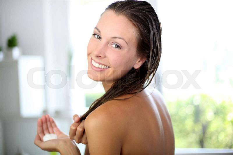 Gorgeous woman putting conditioner in her hair, stock photo